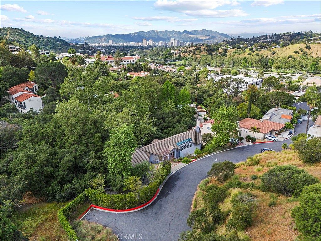 Aerial reveal of 1864 Arvin Drive, the residence set into the southern slope of the Verdugo foothills with downtown Glendale beyond