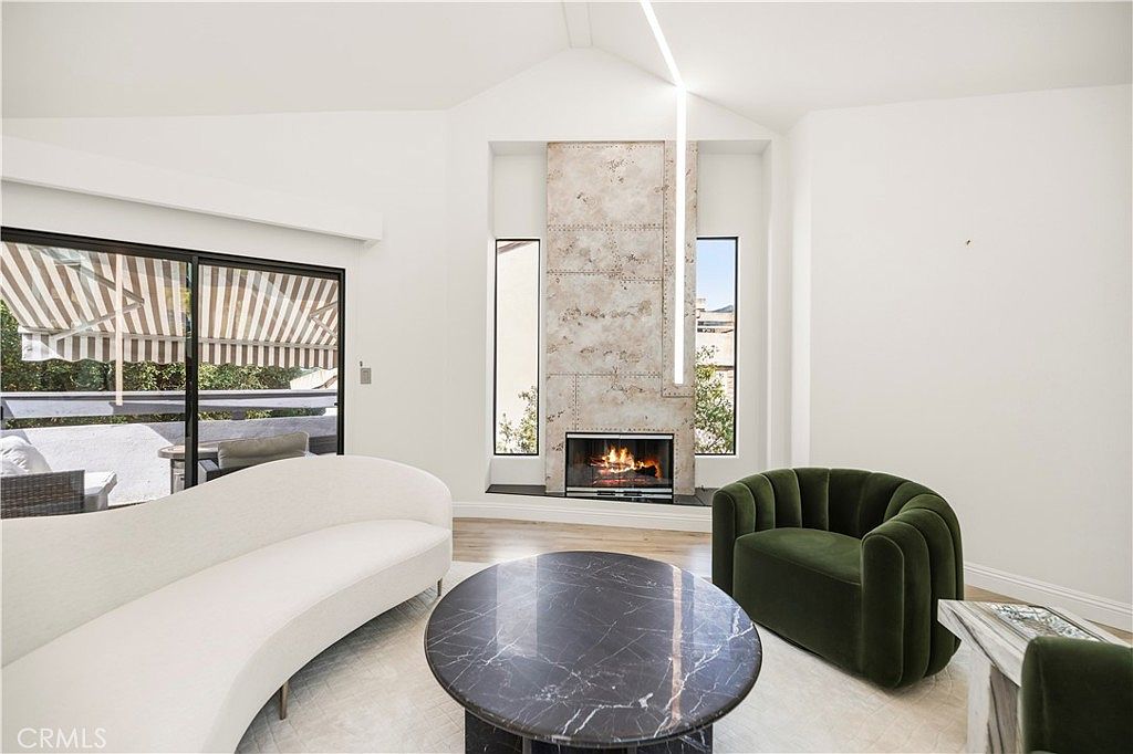 Living room from the side showing the double-height fireplace and green velvet chair
