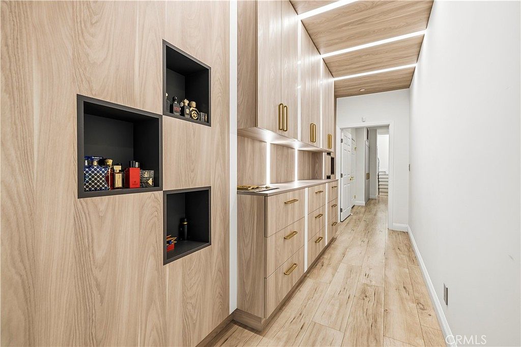 Walk-in dressing room with linear LED uplighting and blonde wood cabinetry